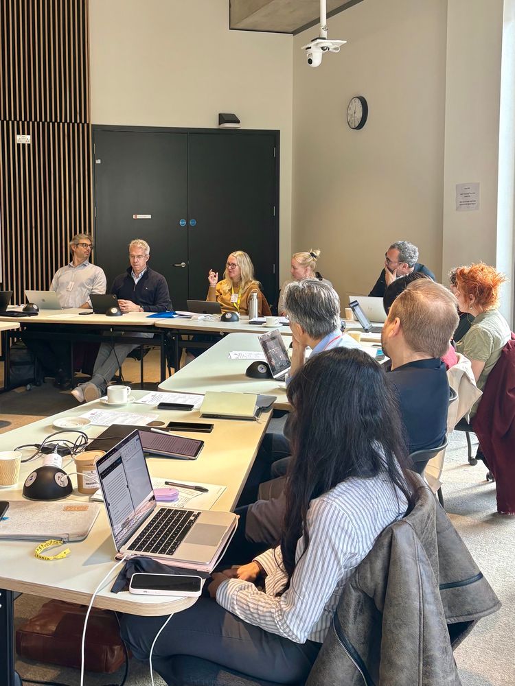 A group of researchers sit and talk around a table 