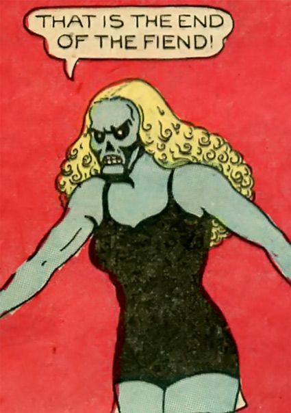 A blue-skinned woman with curly blonde hair and a skull face says: "That is the end of the fiend!" 
