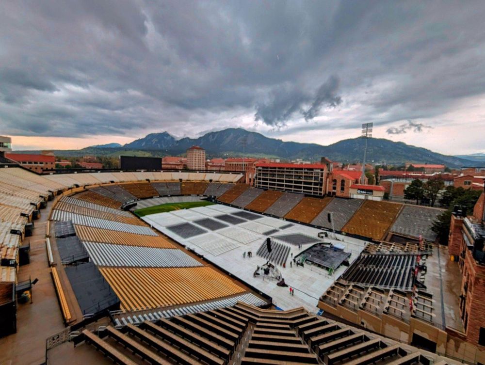 Folsom Field with stage and seats set up for Commencement. Grey skies with the Flatirons in the background