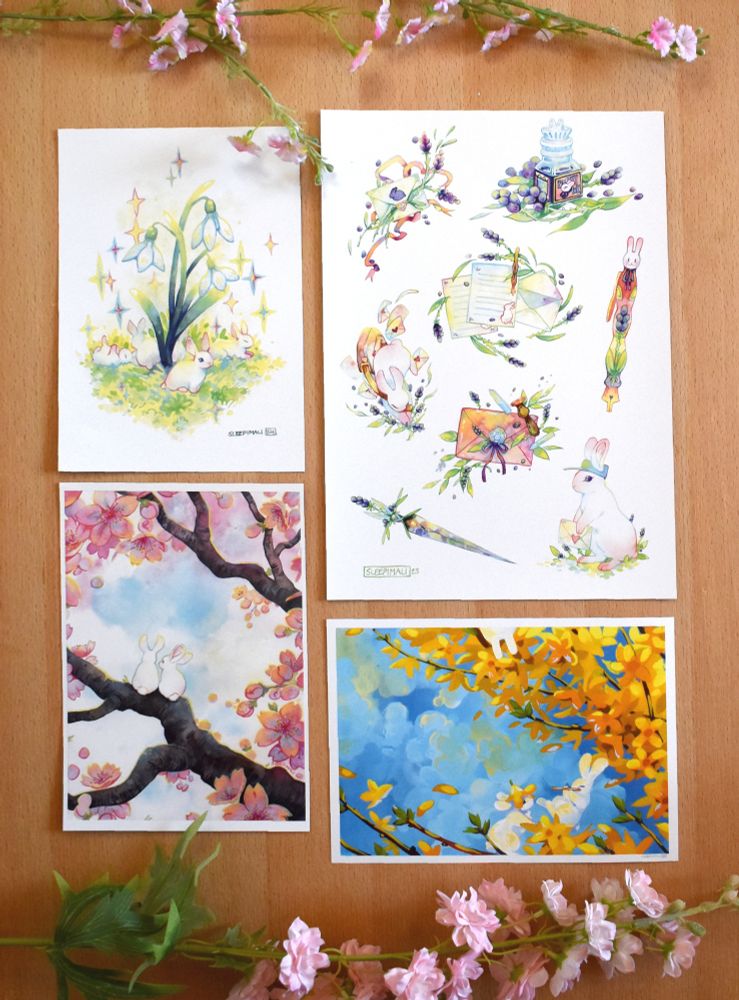 Flatlay of four different prints featuring themes of bunnies and flowers
