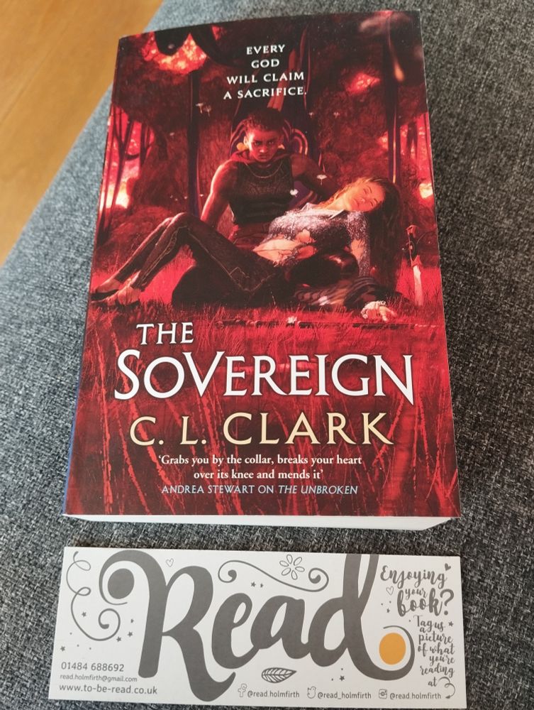 C.L. Clark's new book, The Sovereign, on my sofa, with a bookmark from the independent bookshop where I got it 
