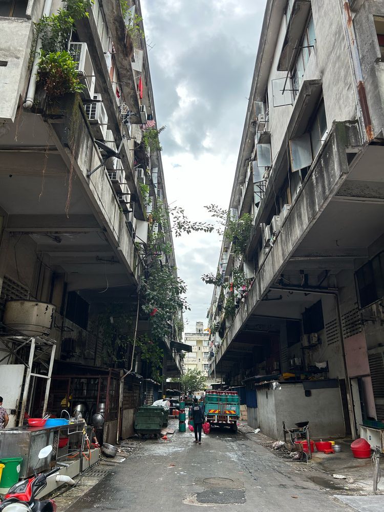 An alleyway with pedestrians walking past goods delivery vehicles delivering items
