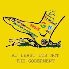 variação da bandeira de gadsden, mostrando uma cobra sendo pisada por um pé em que estão logos de diversas empresas, como coca-cola, walmart, exxon, etc.
embaixo dela, está o texto "at least it's not the goberment
