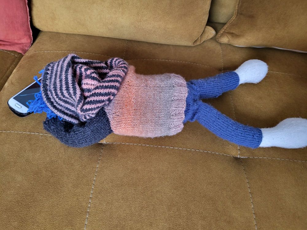 Wollpuppe die mit dem Gesicht nach unten auf dem Sofa liegt