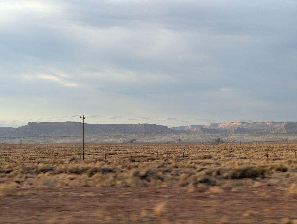 Countryside flying by.from the passenger seat. There are mesas in the distance. 
