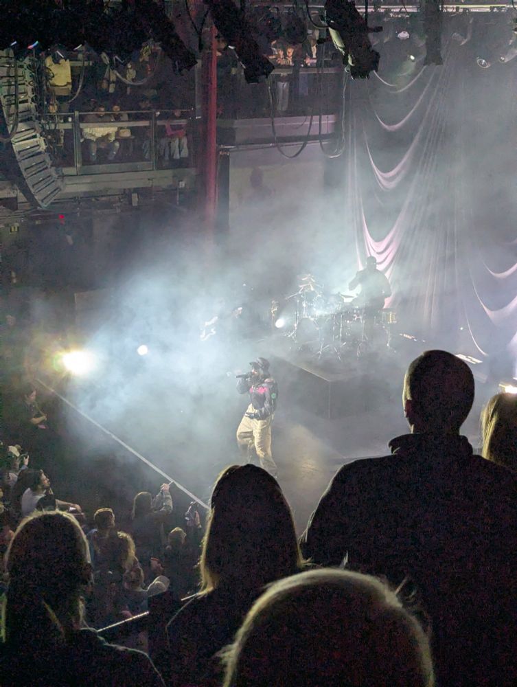 Little Simz performing on a stage, through smoke. 