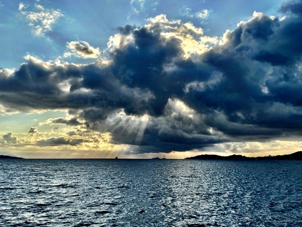Stormy dark cloud over the bay, with rays of dawn sunshine breaking through.