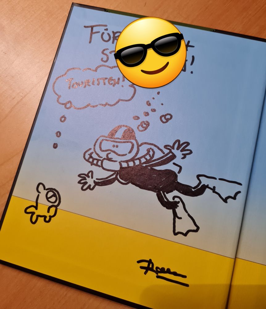 Eine, von Ralph Ruthe gezeichnete Taucherin, vor der ein schlecht gelaunter Fisch schwimmt. Über den Fisch eine Denkblase mit dem Wort "Touristen" drin. Über den Bild eine Widmung, die mit einem Smiley unkenntlich gemacht wurde, drunter die Unterschrift von Ralph Ruthe.