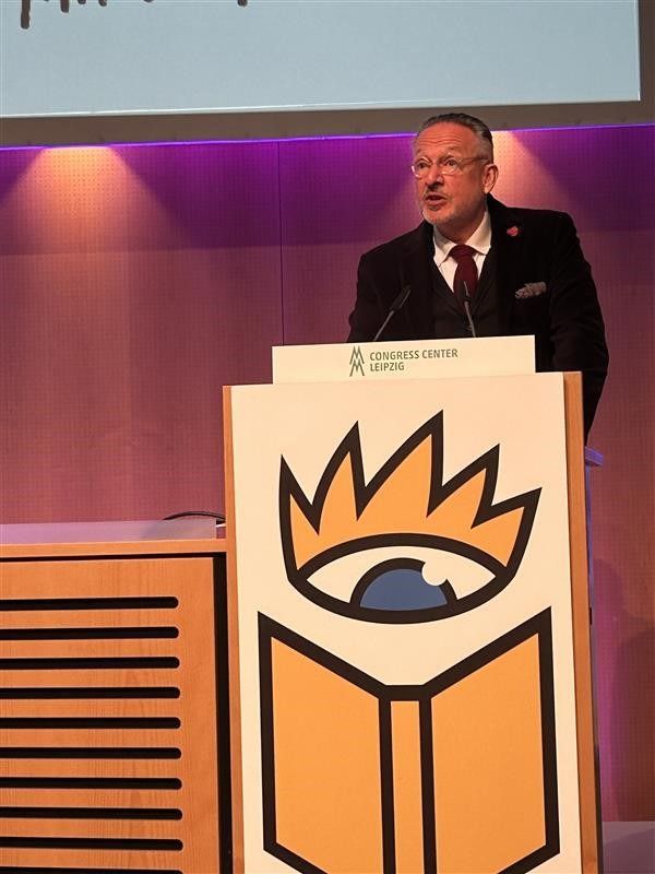 Peter Kraus vom Cleff spricht auf der Eröffnungs-Pressekonferenz und steht dabei auf einer Bühne hinter einem Stehpult mit dem Logo der Leipziger Buchmesse 