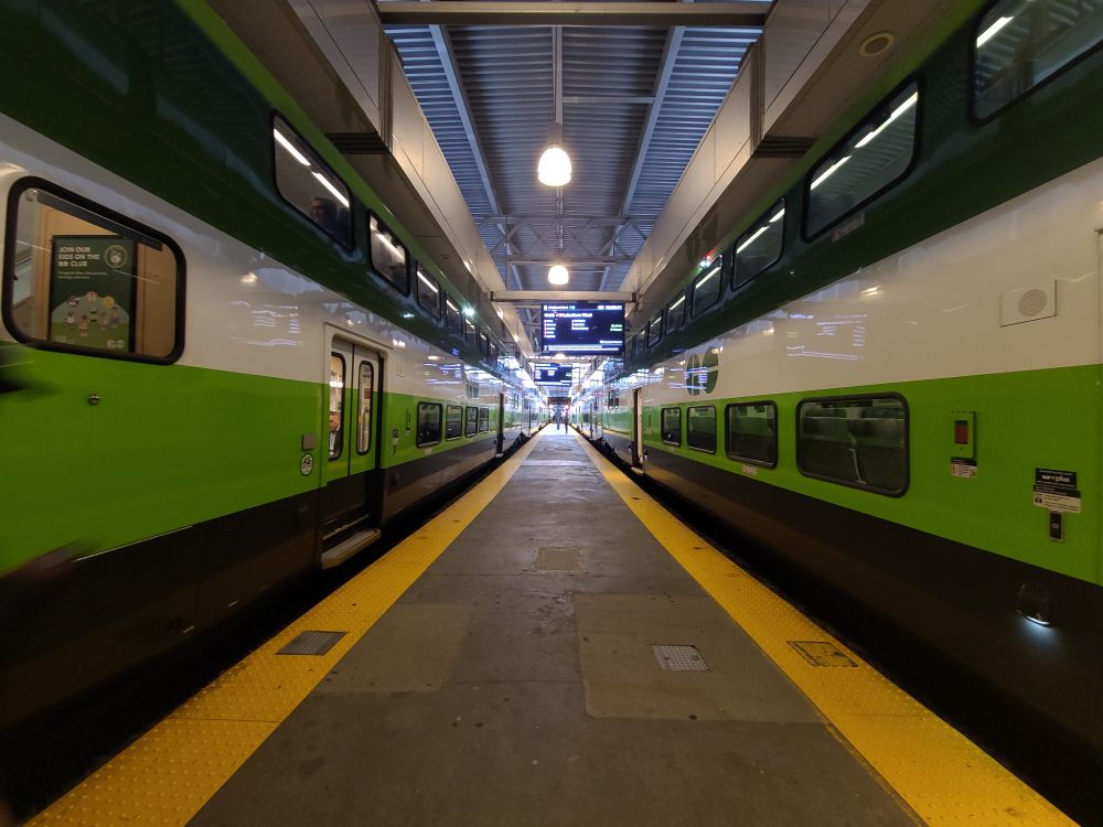 Photograph looking down a platform with two GO Transit trains on either side