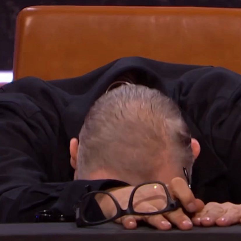 Greg Davies on Never Mind The Buzzcocks, glasses removed, face pressed down into the desk in despair. 