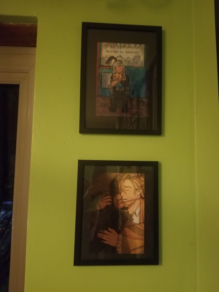 Two prints one above the other on black frames. The top is baby kraken of ed with his bear. The grab machine thingy he got it from is behind him and he has clearly lost the sleeve of his leather jacket retrieving teddy. The lower one is sted in his battle jacket embracing ed.