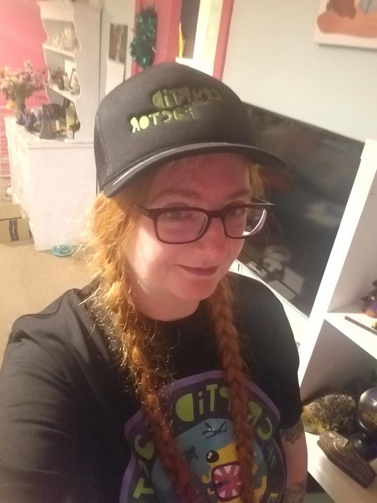 Me! Pale with ginger pigtails. Am wearing a black tshirt with the cryptid factor logo on it and a hat saying the cryptid factor on it.