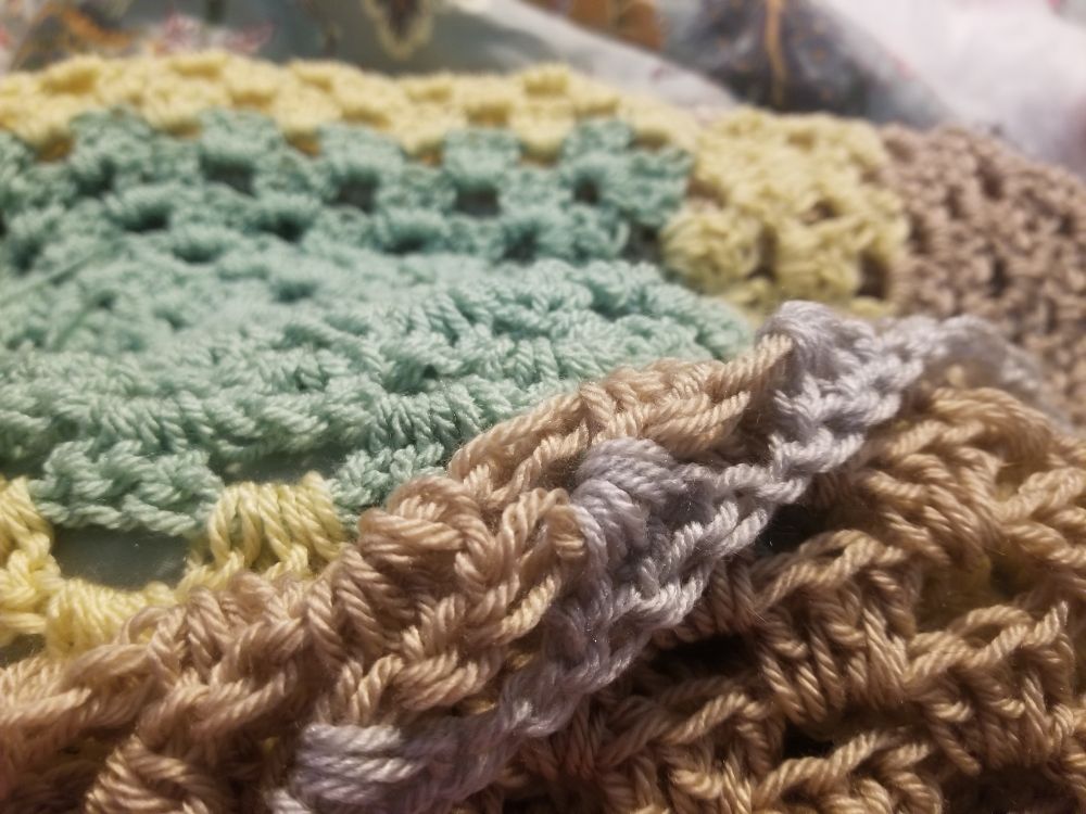 Green, yellow,  golden beige and a silver blue yarns worked in an increasing happily wandering granny square. A symphony in crocheted neutrals.