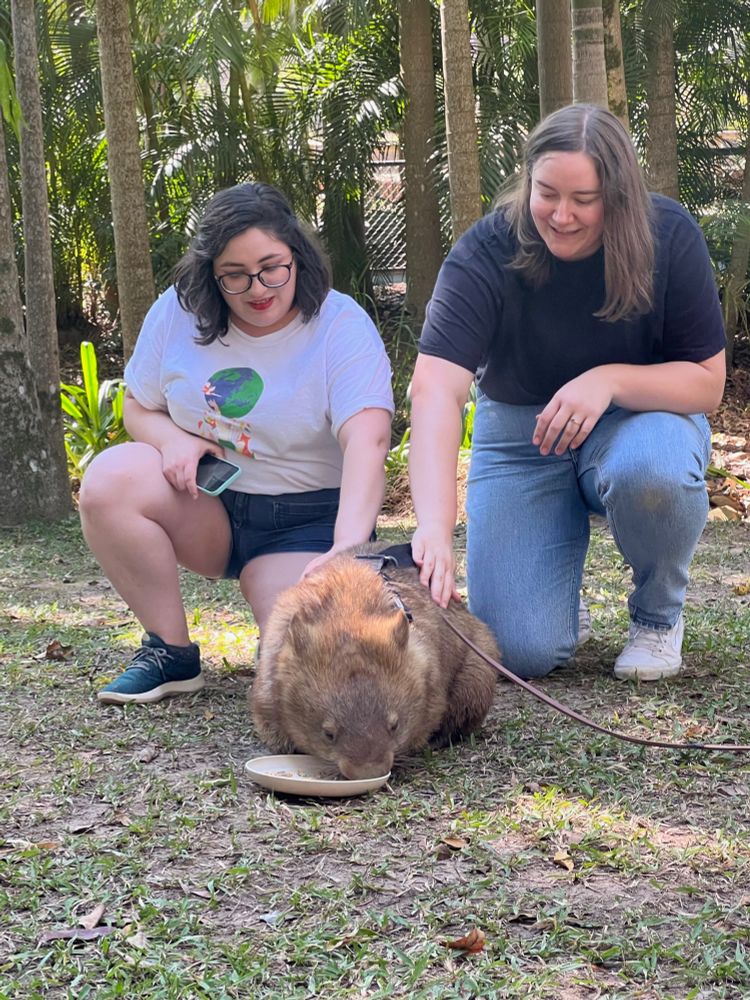 two women petting a wombat