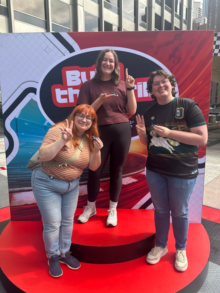 three friends on a red podium posing with their minifig F1 cars