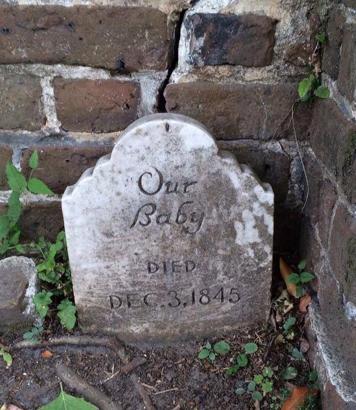 It shows the gravestone of an unbaptized baby placed just outside the cemetery wall.  