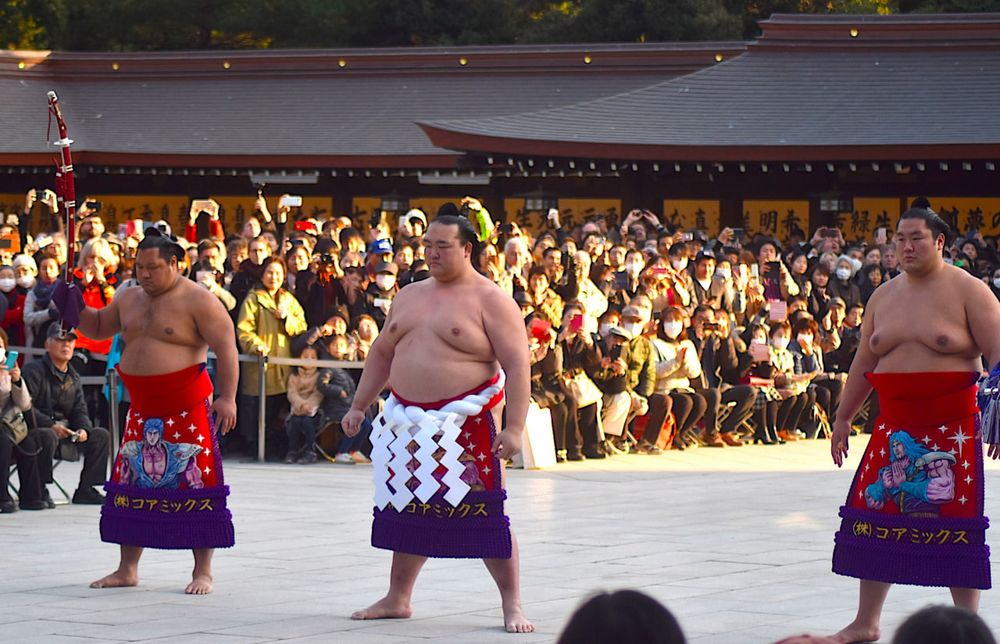 Imagem da cerimônia de entrada (dohyo iri) do Yokozuna Kisenosato no Santuário Meiji. Kisenosato e seus atendente usam um avental cerimonial que retrata os personagens Kenshiro, Raoh e Toki de Hokuto no Ken. Da esquerda pra direita a imagem mostra os atletas Shohozan (carregando uma espada), Kisenosato e Kagayaki.