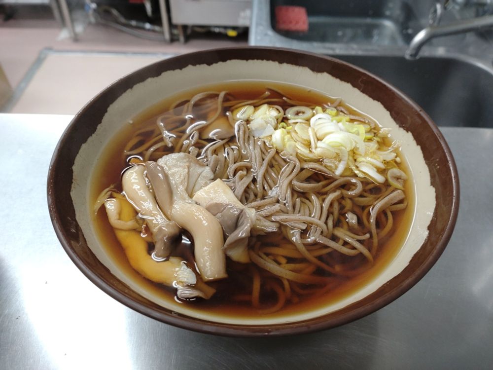 きのこ蕎麦。冷凍麺にきのこ、刻み葱が乗っている。