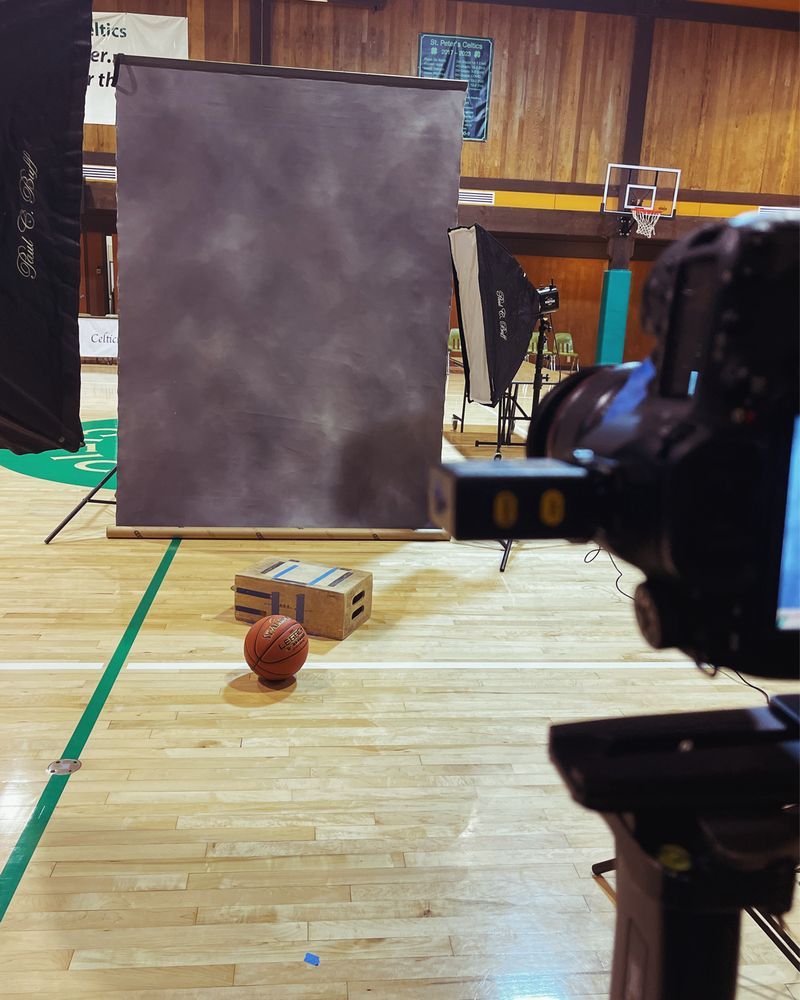 A portable photography studio set up inside a gym, complete with lighting and equipment, ready for basketball players to take their portraits