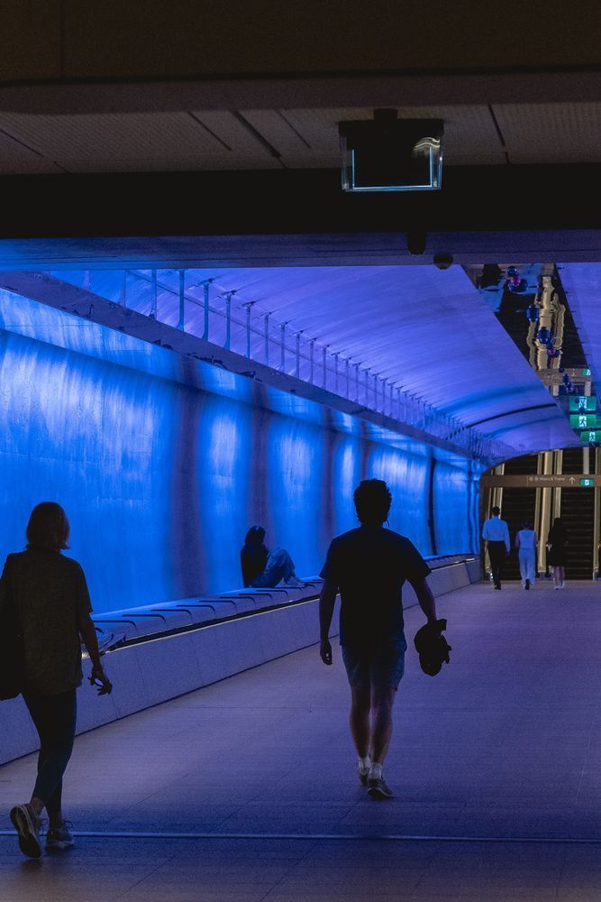 Martin Place Metro’s underground pedestrian link tunnel, Muru Giligu, illuminated in blue hues as people move through the space