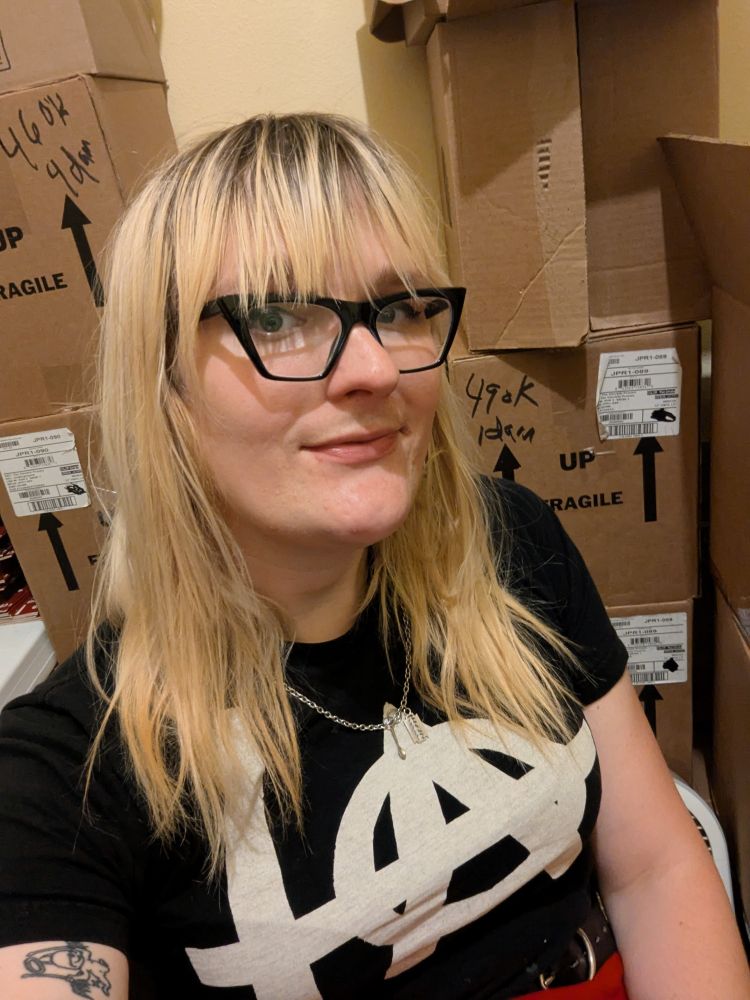 Me, Kim, smiling in front of stacks of cardboard boxes 