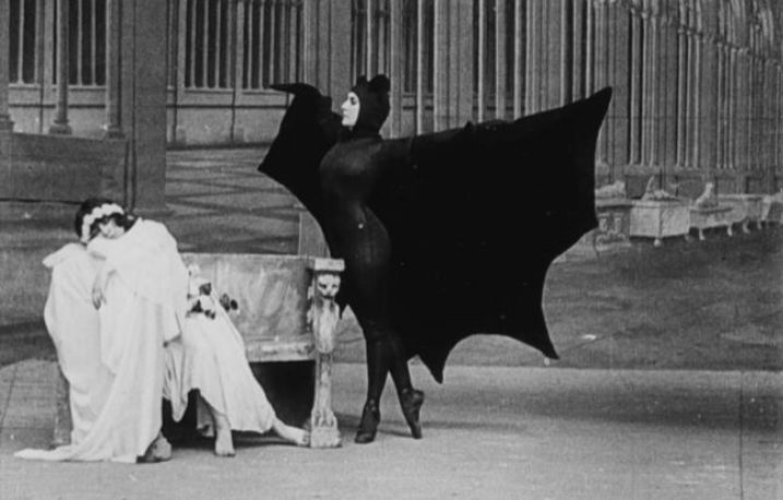 famous scene from les vampires in which a play is unfolding in which a women is dressed as a vampire and is menacing a sleeping women 