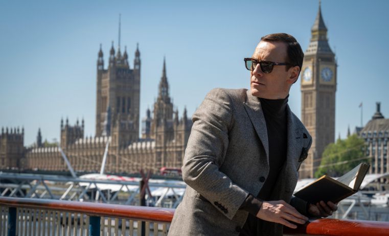 michael fassbinder on a bridge in front of the houses of parliament 