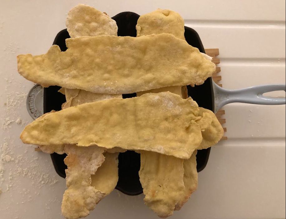 carta di musica in a cast iron pan from above arranged two one way then two the opposite way like a jenga tower 