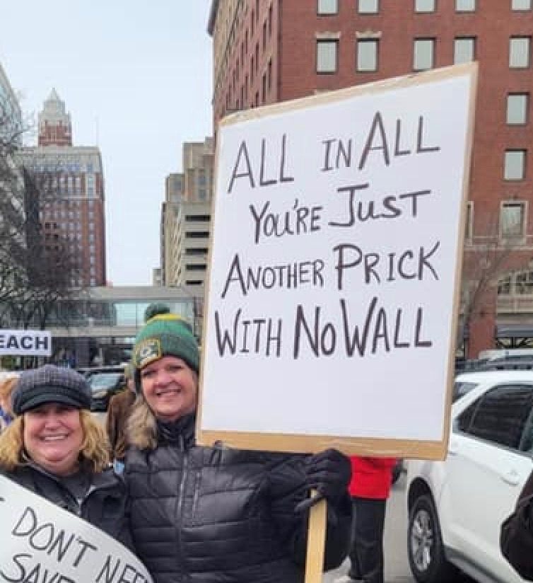 Protest sign that

“All in All
You’re Just
Another Prick
With No Wall”