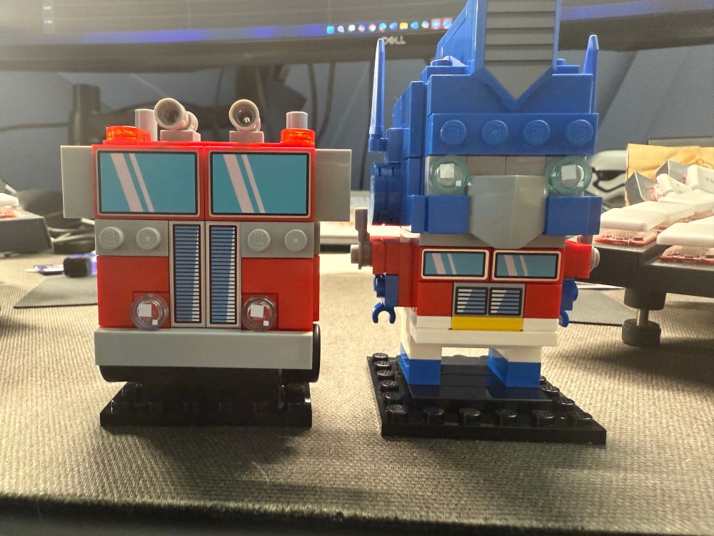 Optimus Prime truck and robot form Lego brick heads set sitting on a desk mat