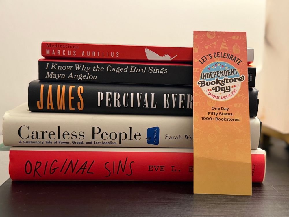 Stack of books with bookmark that says let’s celebrate independent bookstore day. 
Books include
Meditations -Marcus Aurelius
I know why the cage bird sings - Maya Angelou 
James - Percival Everett
Careless People - Sarah Winn-Williams
Original Sins - Eve L. Ewing 