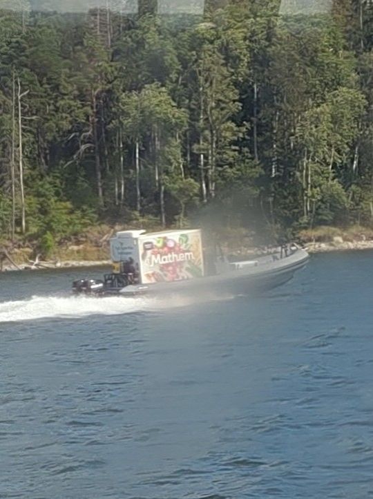 A small boat travelling at high speed, with a large box in the boat marked "Mathem"