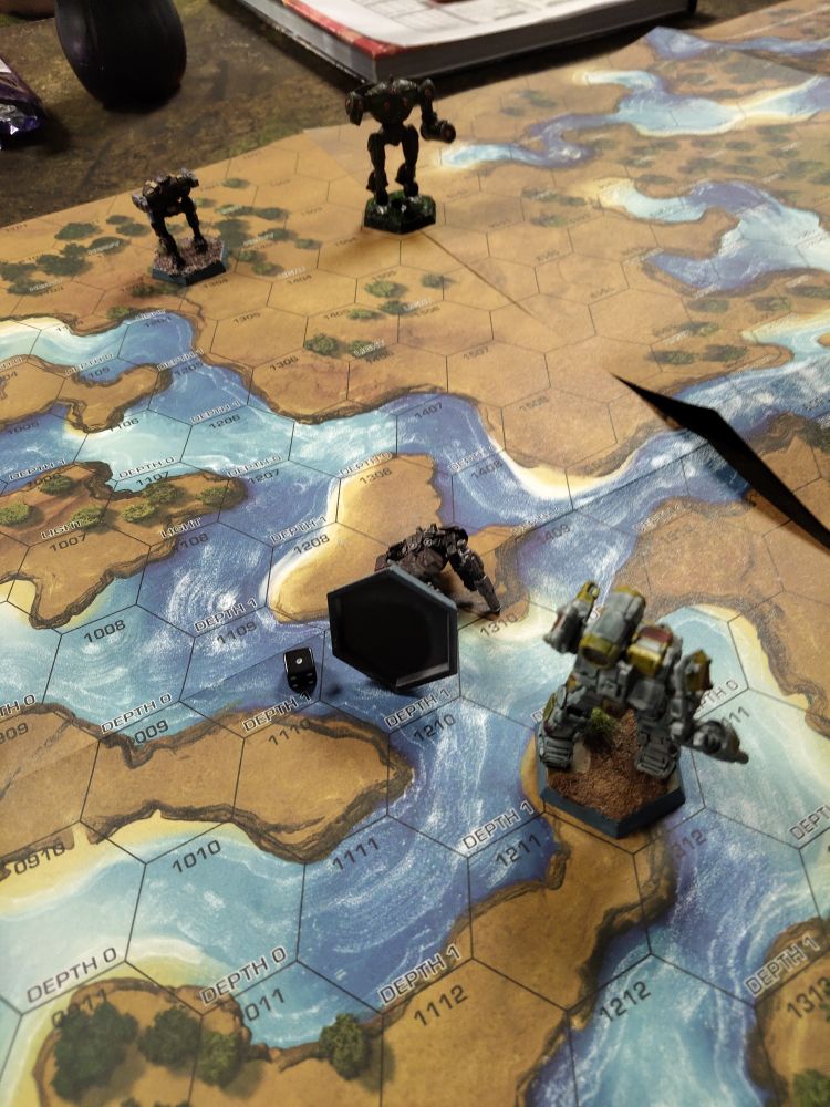 Scene from a battletech game. A mech is lying sideways in a water hex