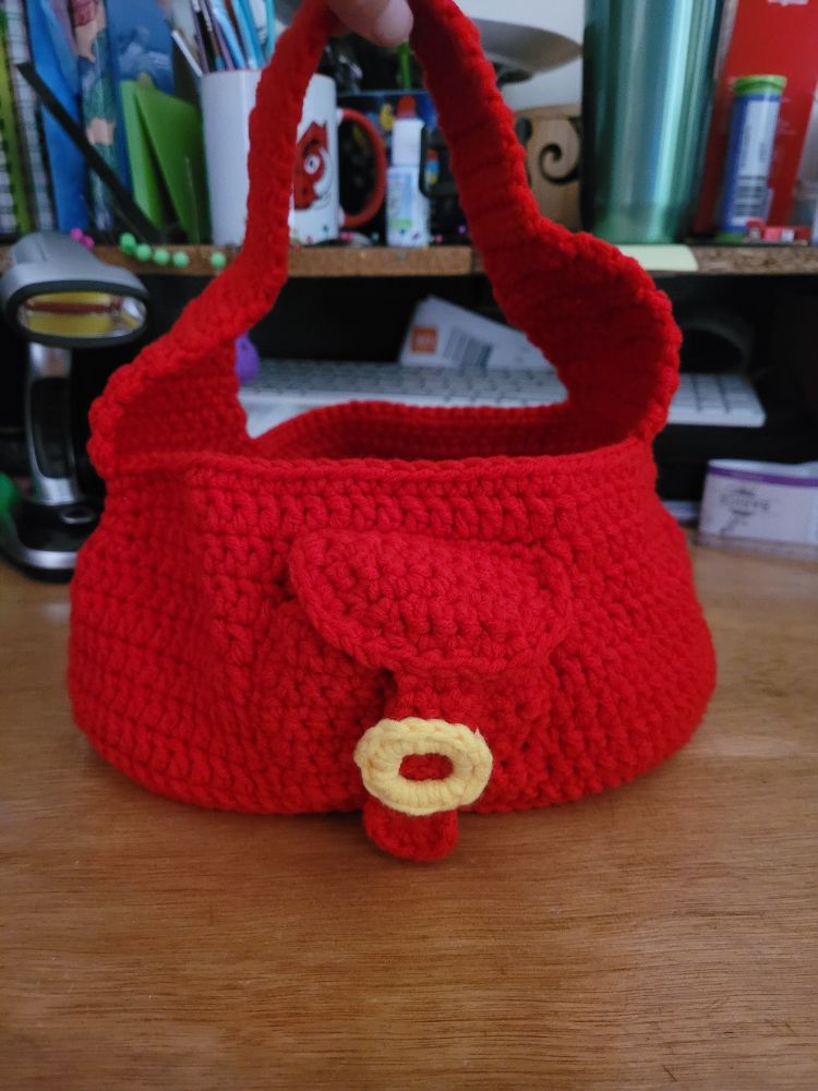 Crochet 🧶 small red handbag. Oval base, 1 over-shoulder strap, small pocket on side/front of bag with crochet yellow buckle.