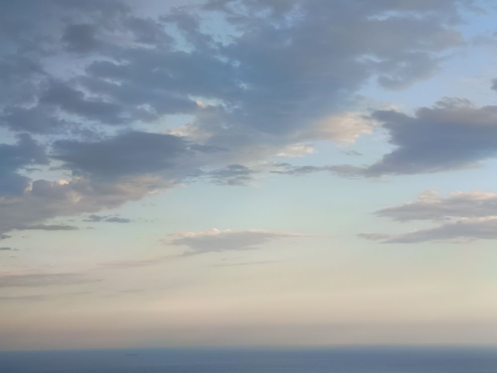 Some clouds, the last sun rays far away and the blue sea.