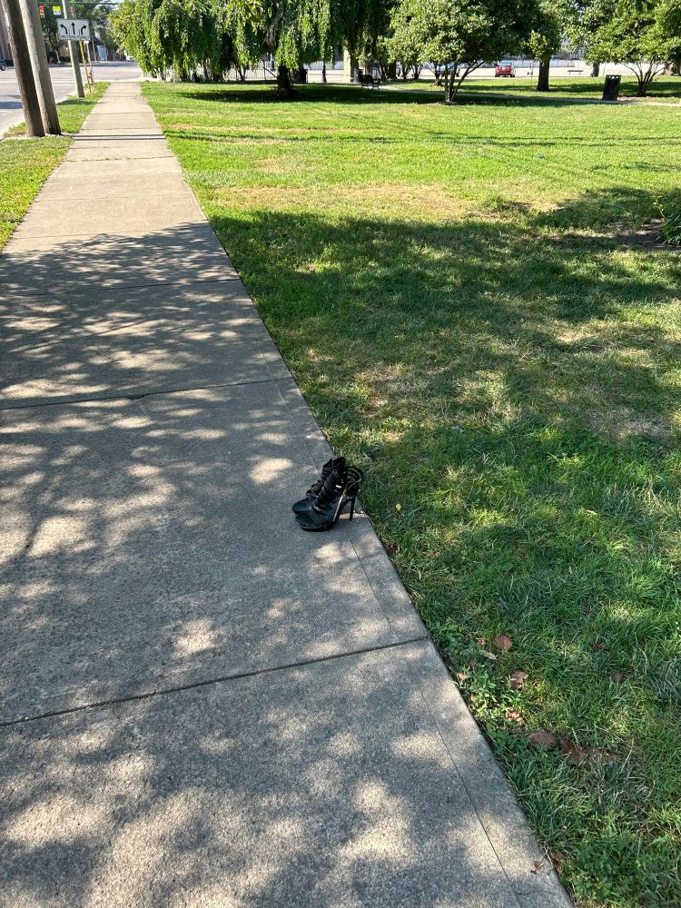 walking path in a park. two black lace up high heels left perfectly aligned with the edge of the path