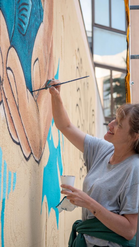 Mural artist Jen Miller painting entry wall.