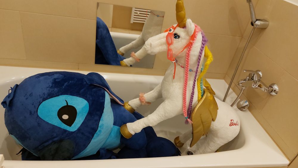 In einer Badewann ist ein riesiges Stich-Kuscheltier und ein riesen Einhörn gestapelt 