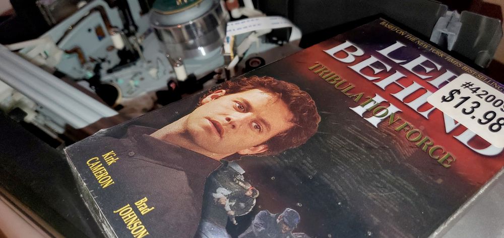 A VHS copy of Left Behind II sits on an open VCR with the guts exposed.