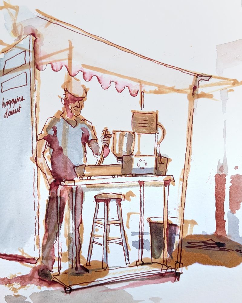A man works a deep fryer to make donuts in a pop up stall. The sketch style utilizes the water-soluble maroon ink to create transparent shades across the figure.