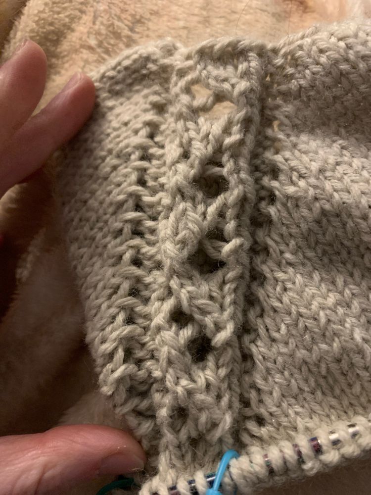 Close up of a knitting project. Some of the off-white lace is out of alignment with the rest of the pattern
