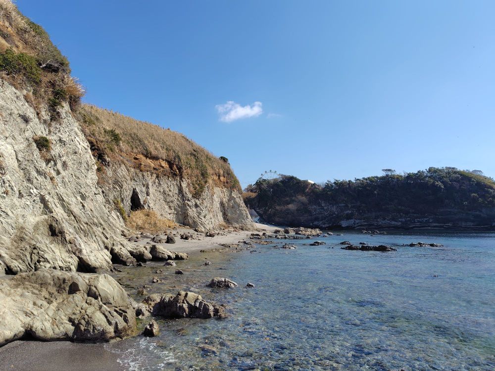 Cliffs on left bordering the sea. A Ferris wheel is visible on top of a forested cliff