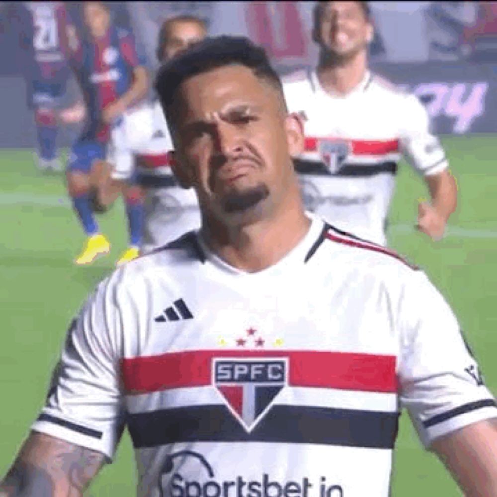 a man in a soccer jersey is making a funny face while standing on a field .