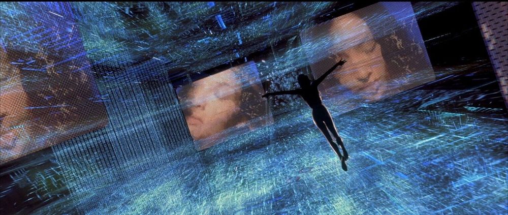 A film still from Tomorrow Never Dies (1997, Roger Spotiswoode). The silhouette of a woman spreads out against a sea of digital screens and cybernetic artifacts. 