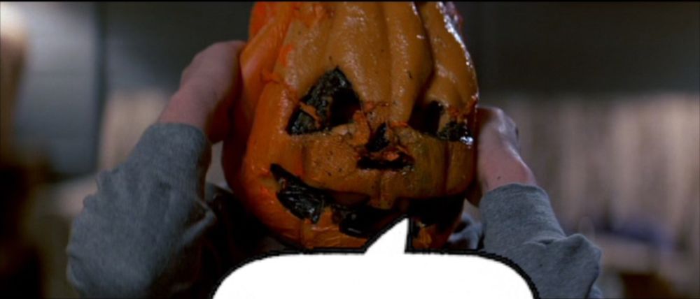 A film still from Halloween III: Season of the Witch (1982, Tommy Lee Wallace). A kid in a melting pumpkin mask clutches his head in agony as he is transmogrified into a goopy pile of meat, bones, bugs, and snakes. 