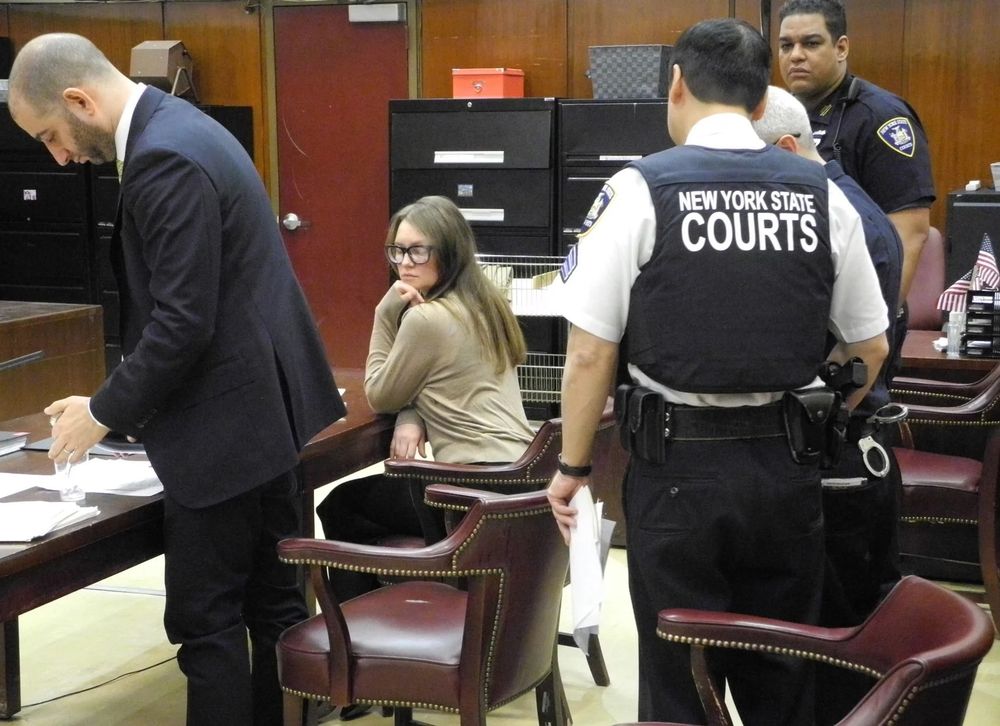 Anna Delvey finally has her day in court. Seen here, she sits at the defendant's desk in New York state court, surrounded by bailiffs and her defense lawyer.