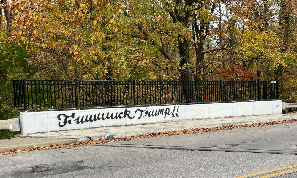 Bridge with graffiti that says Fuuuuuuck Trump!! in cursive