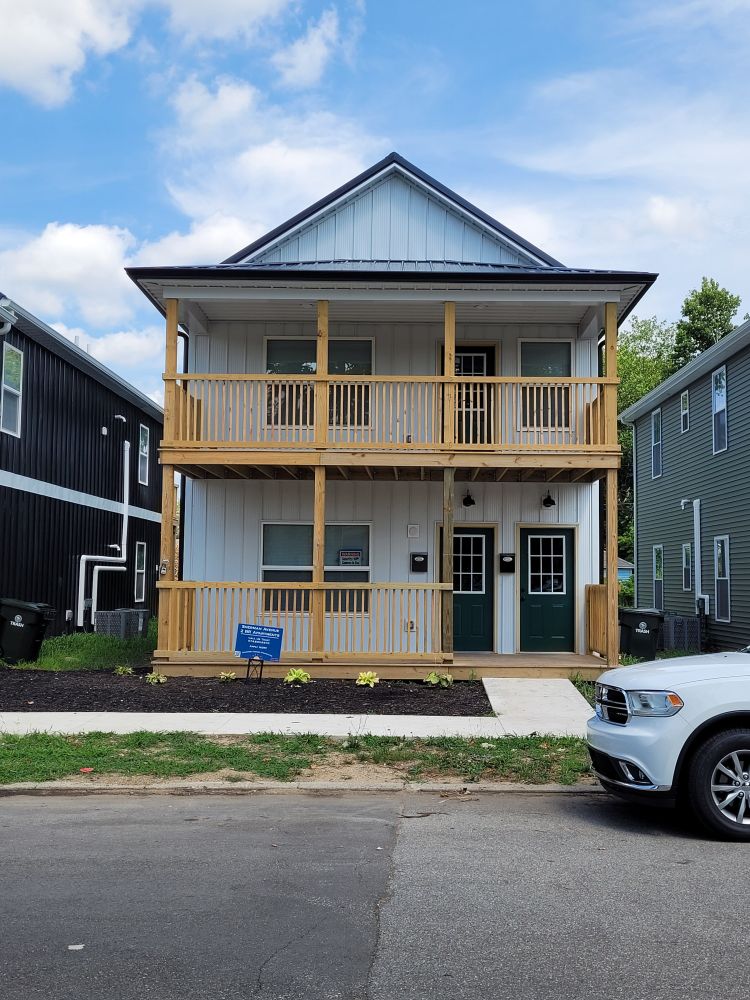 White-sided duplex with a two-story porch and green doors