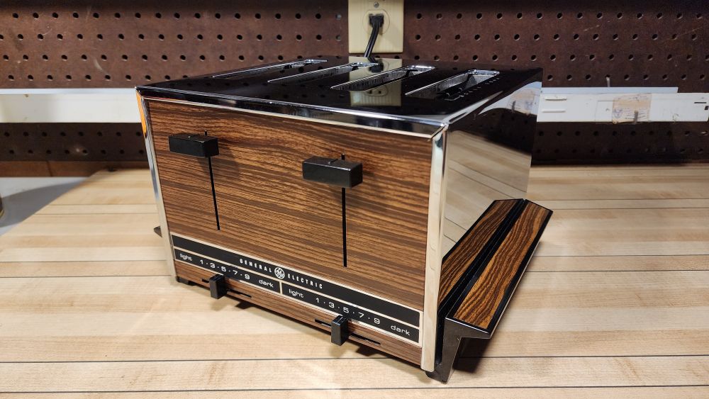 Photograph. A 1970s General Electric 4-slice toaster styled in chrome and fake woodgrain. 